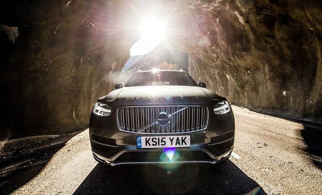 Black Volvo driving through a rocky tunnel
